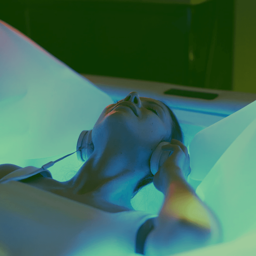 Client with headphones relaxing on dry float bed at Zivel
